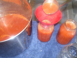 Pouring hot tomato sauce in sterilized canning jars